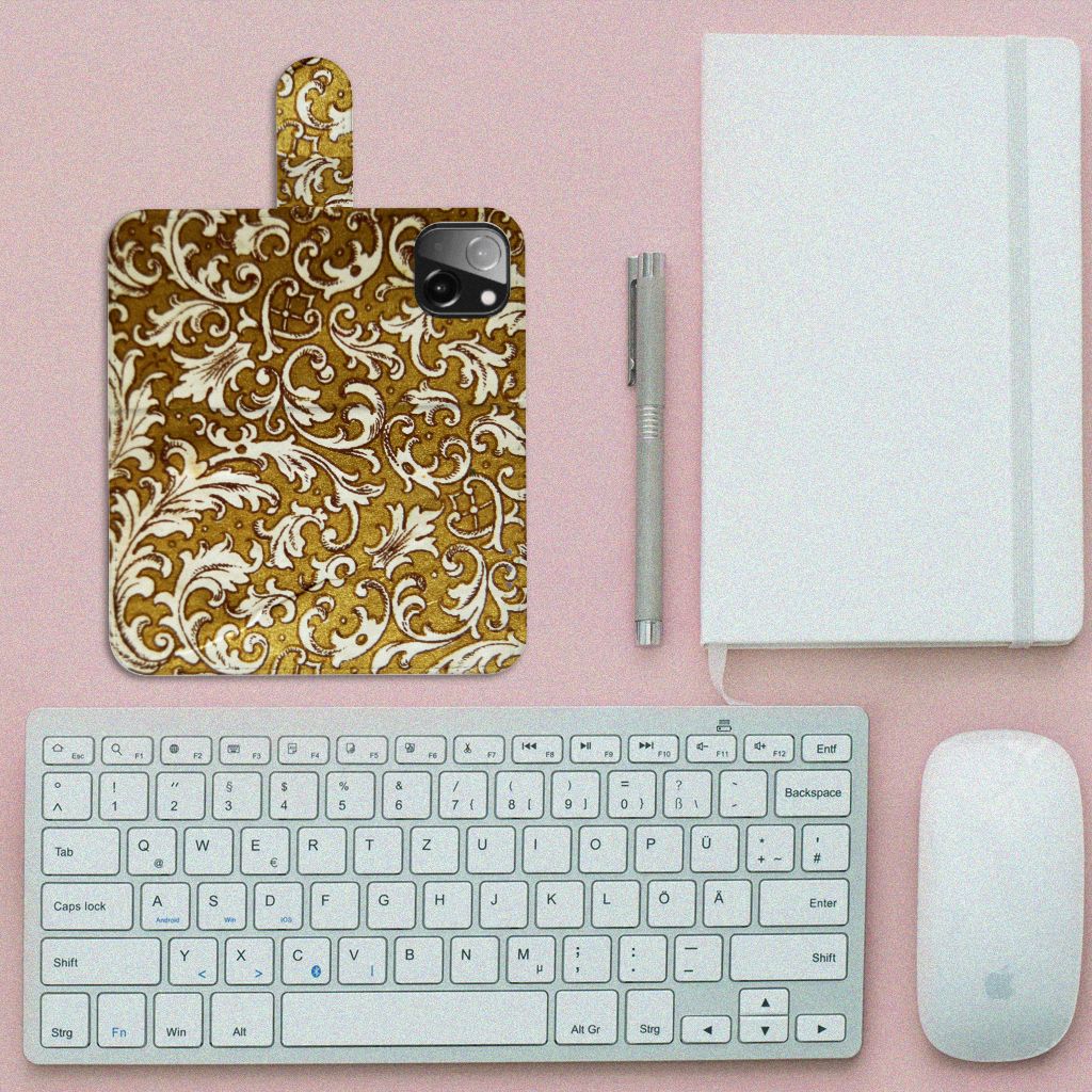 Wallet Case iPhone 13 Mini Barok Goud met elegante barokdesign op een roze achtergrond met toetsenbord en notitieboek.