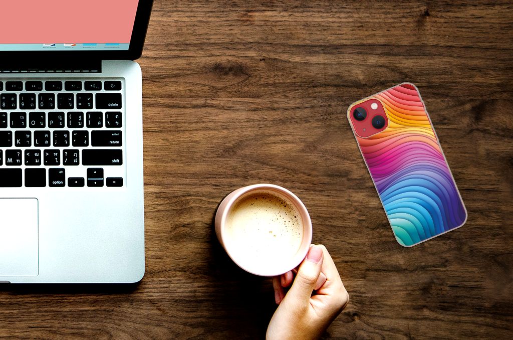 TPU Hoesje voor Apple iPhone 13 Regenboog ligt naast een laptop met een hand die een kop koffie vasthoudt.