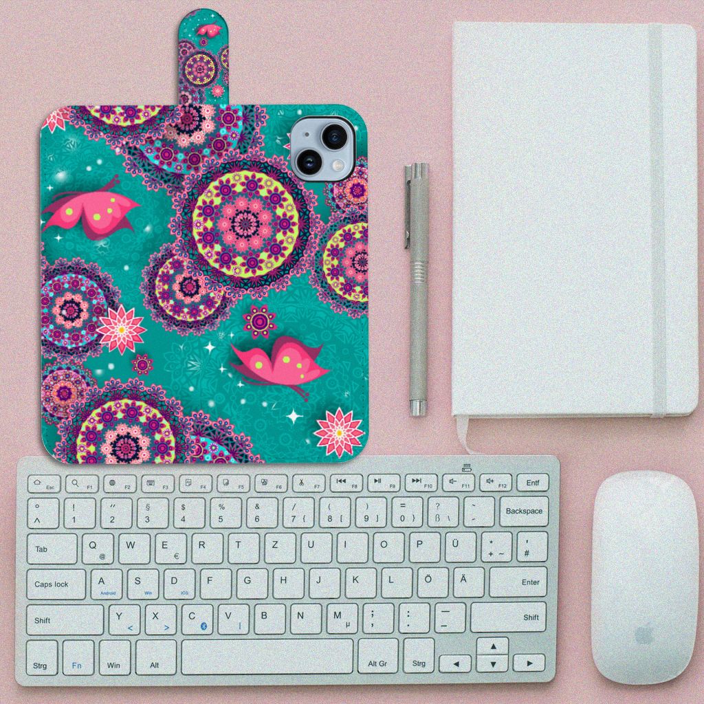 iPhone 15 Plus Hoesje Cirkels en Vlinders met kleurrijk mandala-desig en vlinders đ¸ op een bureau met toetsenbord en notitieboek.