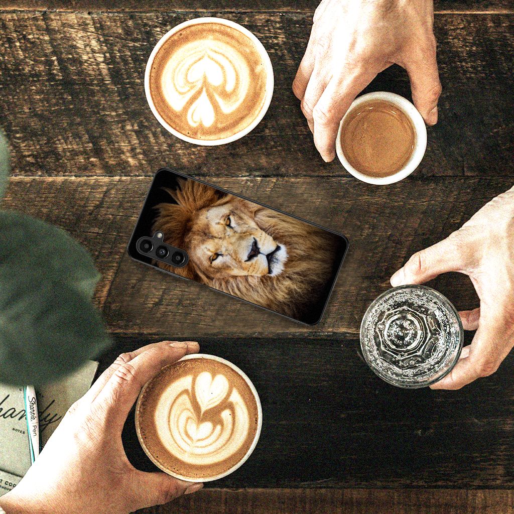 Samsung Galaxy A14 5G Dierenprint Telefoonhoesje Leeuw op een houten tafel met koffie en glazen water.