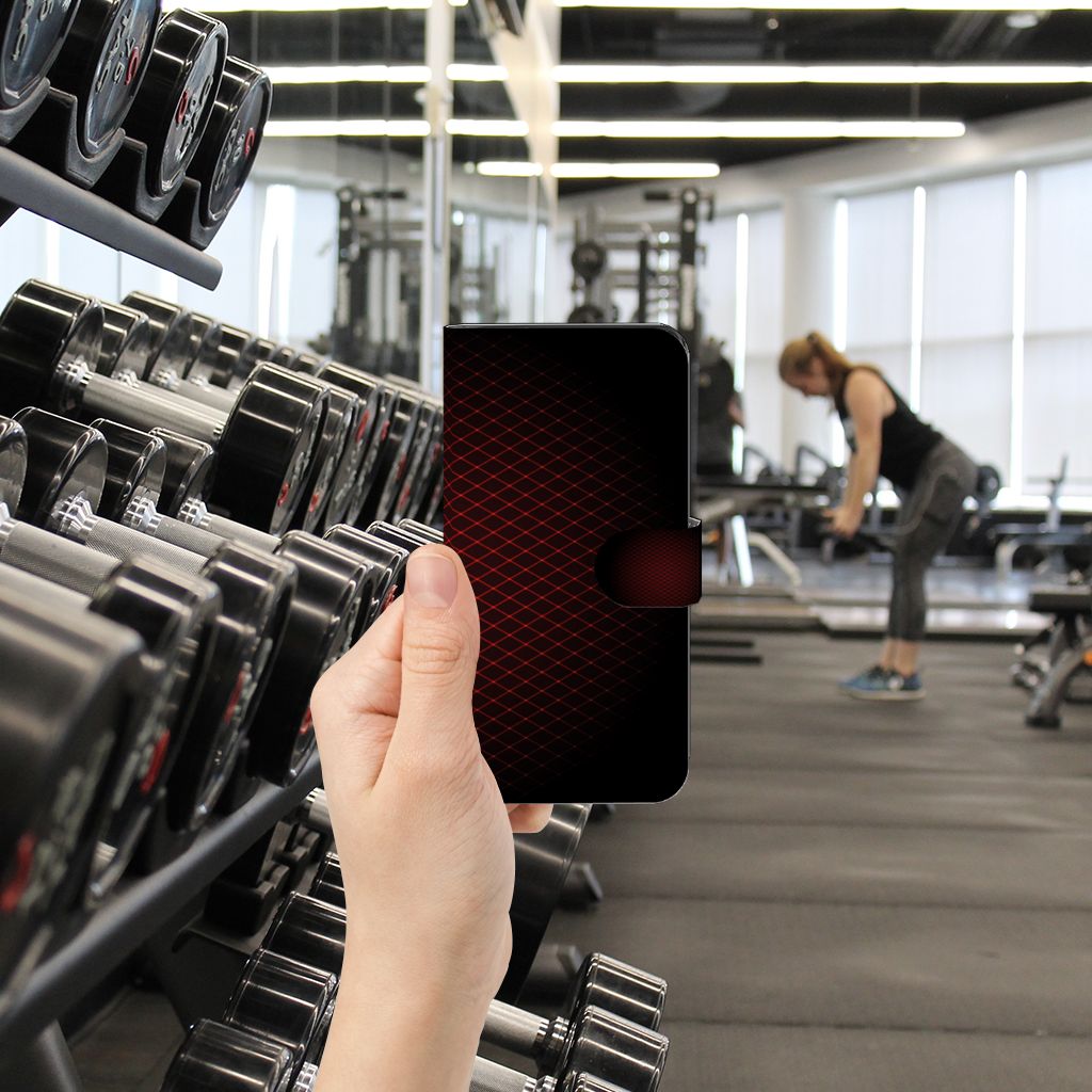Google Pixel 7A Telefoon Hoesje Geruit Rood in hand, fitnessruimte met gewichten op de achtergrond.