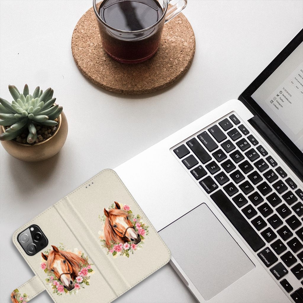 Telefoonhoesje met Pasjes voor iPhone 13 Pro Max Paard ligt naast een laptop en kopje koffie, met een groene plant.