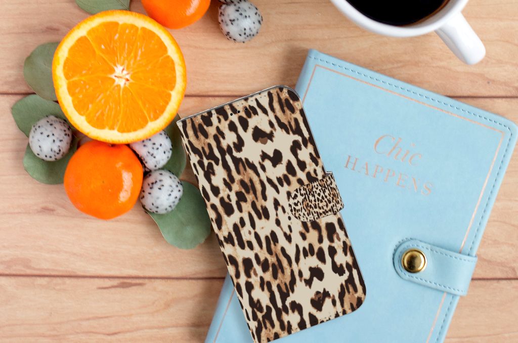 iPhone 14 Plus Telefoonhoesje met Pasjes Leopard op een tafel met fruit en een notitieboek.