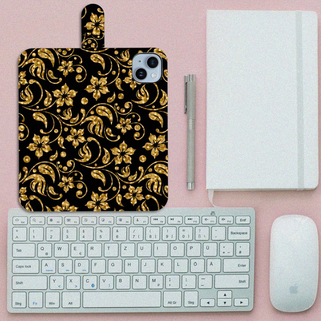 iPhone 15 Plus Hoesje Gouden Bloemen met elegant zwart-gouden bloemenpatroon op een bureau