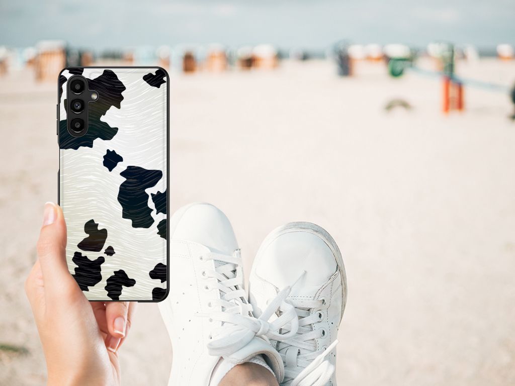 Samsung Galaxy A14 5G Dierenprint Telefoonhoesje Koeienvlekken in handen op het strand met sneakers.