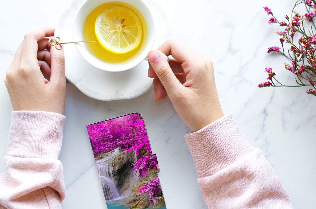 iPhone 15 Flip Cover Waterval naast een kopje thee met citroen en bloemen op de achtergrond.