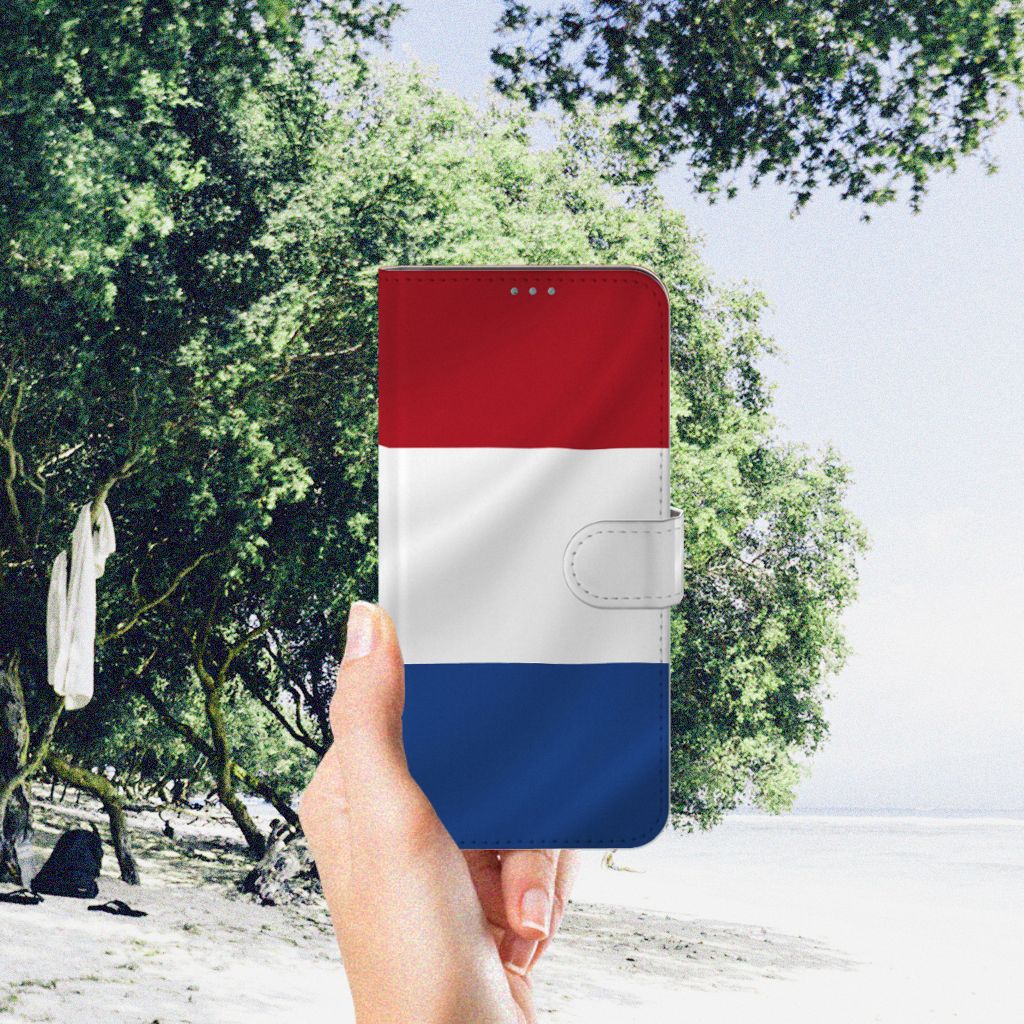 Nokia X10 | Nokia X20 Bookstyle Case Nederlandse Vlag met hand tegen een natuurlijke achtergrond.