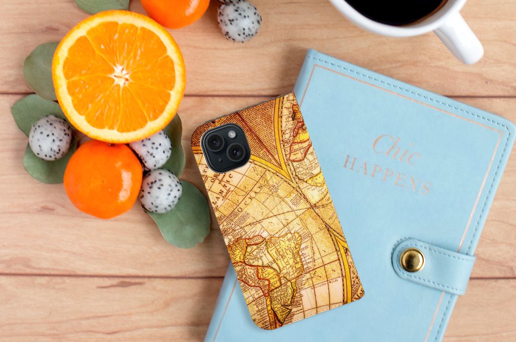iPhone 15 Book Cover Kompas met een vintage wereldkaartdesign en citrusvruchten op een houten tafel.