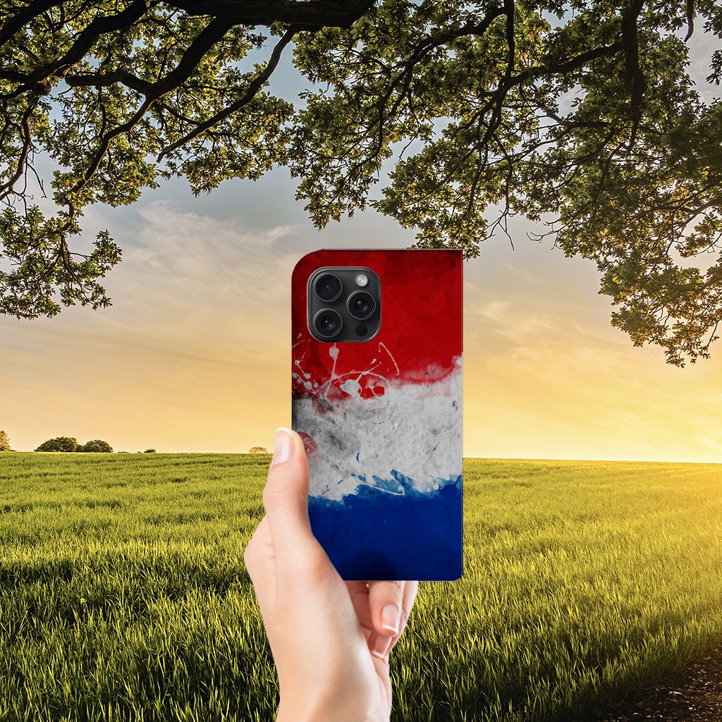 Hand holding an iPhone 15 Pro Max Standcase Nederland with a Dutch flag design in a beautiful natural setting.