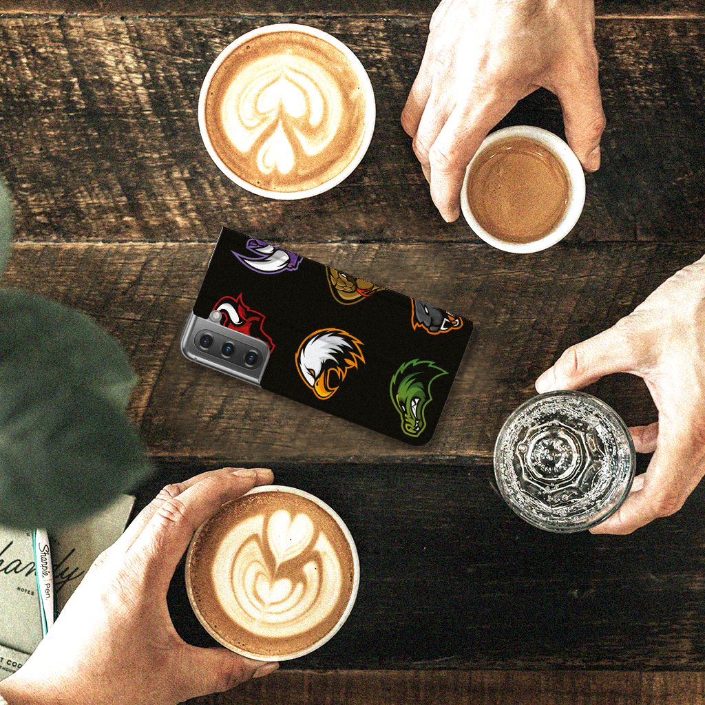 Samsung Galaxy S21 FE Magnet Case Cartoon met verschillende cartoon designs, geplaatst op een tafel met koffie.