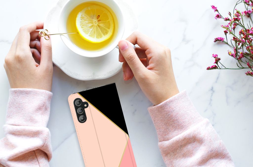 Samsung Galaxy A14 5G Stand Case Zwart Roze Vormen met roze en zwarte vlakken, gebruikt met een kopje thee.