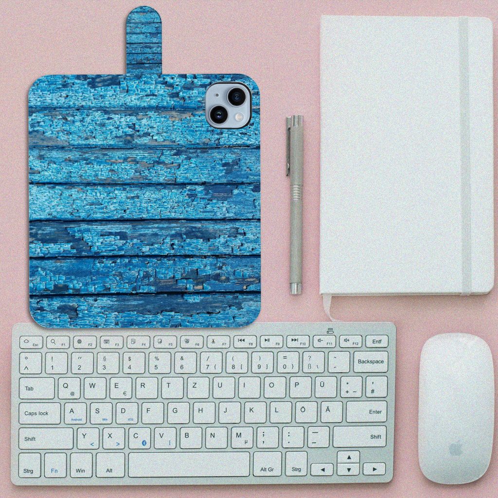 iPhone 15 Plus Book Style Case Wood Blue op een bureaublad met toetsenbord en notitieboek, prachtig blauw houtdesign.