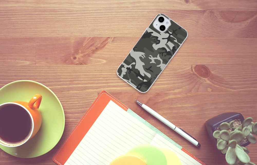 iPhone 15 Plus TPU bumper Army Light met een camouflage print op een houten tafel naast een kopje koffie.