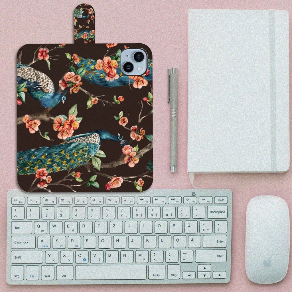 iPhone 15 Plus Telefoonhoesje met Pasjes Pauw met Bloemen op een bureau met een toetsenbord en notebook