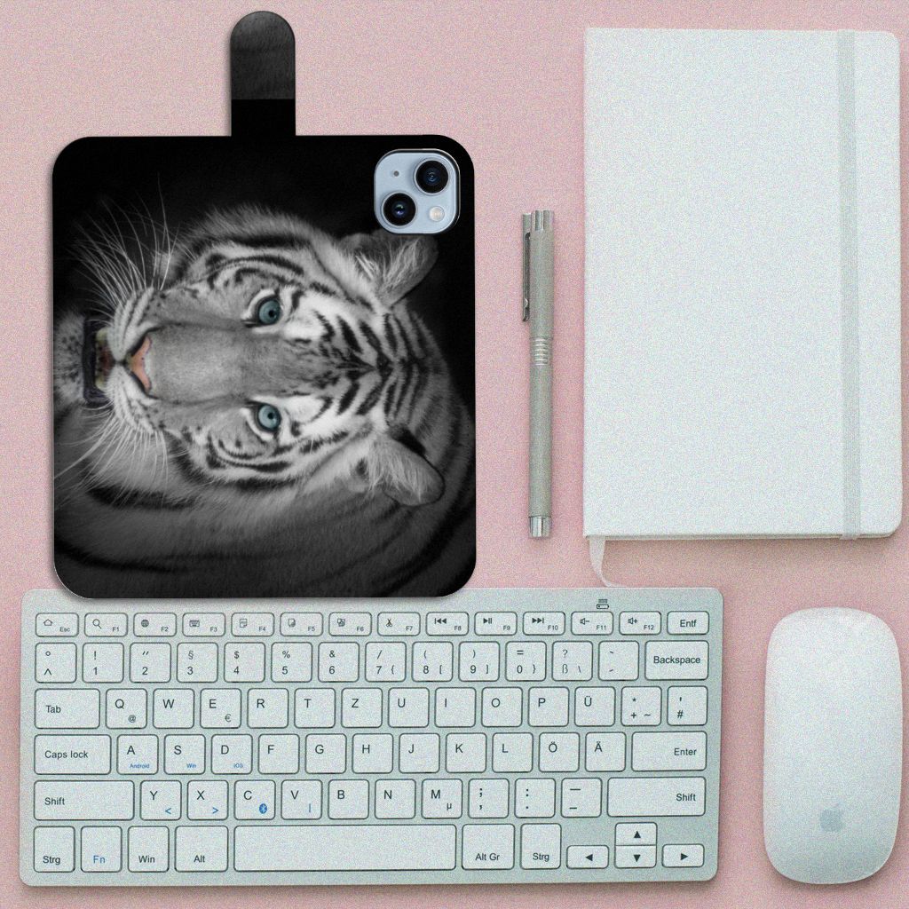 iPhone 15 Plus Telefoonhoesje met Pasjes Tijger met afbeelding van een witte tijger đ
op een bureau.