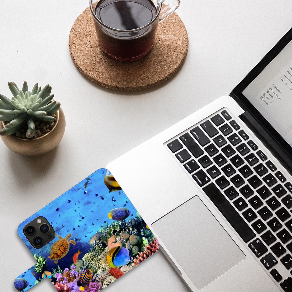 iPhone 15 Pro Telefoonhoesje met Pasjes Vissen met tropische vissen, naast een laptop en een plant.