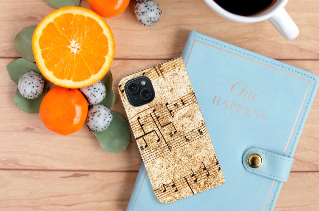 iPhone 15 Stand Case Bladmuziek op een tafel met fruit en een notitieboekje.