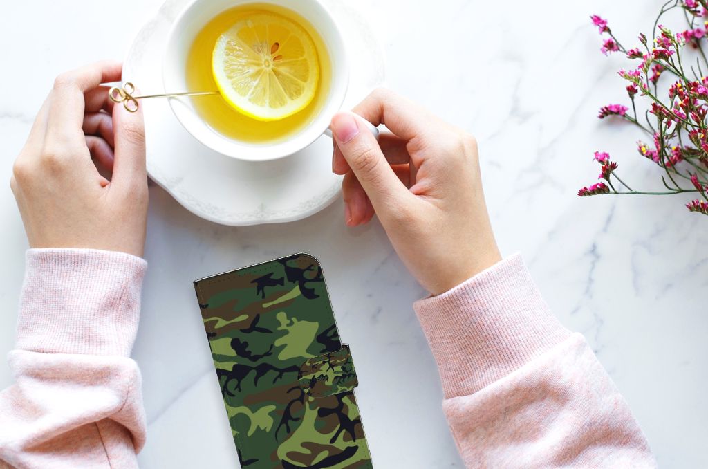 Handen met een iPhone 15 Telefoon Hoesje Army Dark naast een schotel met citroen thee.
