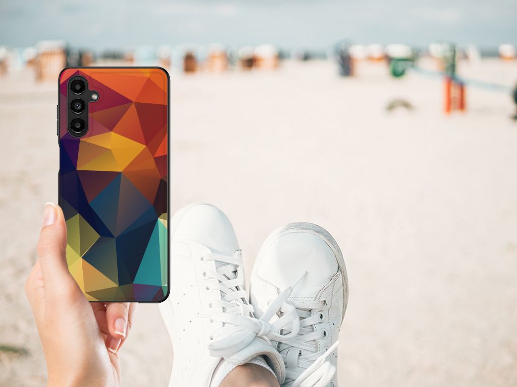 Samsung Galaxy A14 5G Backcover Polygon Color in hand at beach with sneakers on the ground.