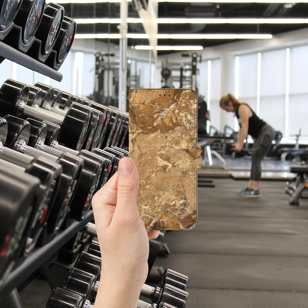 OPPO Find X5 Pro Bookcase Marmer Creme in hand at a gym with weights in the background.