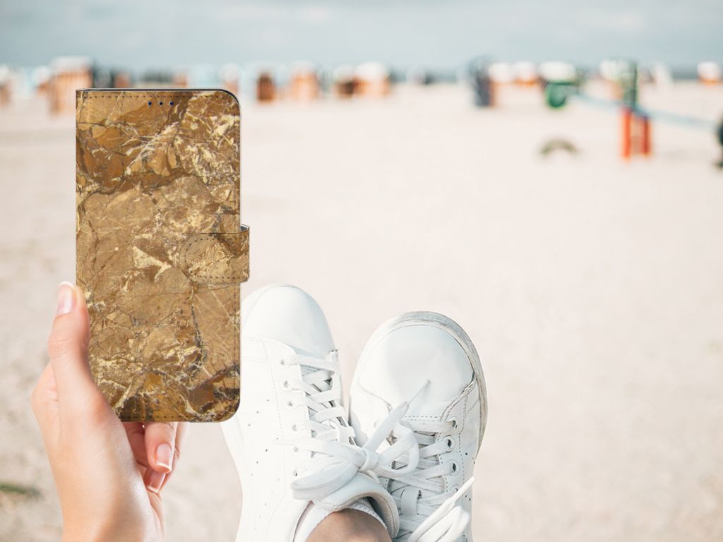 Xiaomi Poco X4 Pro 5G Bookcase Marmer Creme in hand at the beach with sneakers in view.