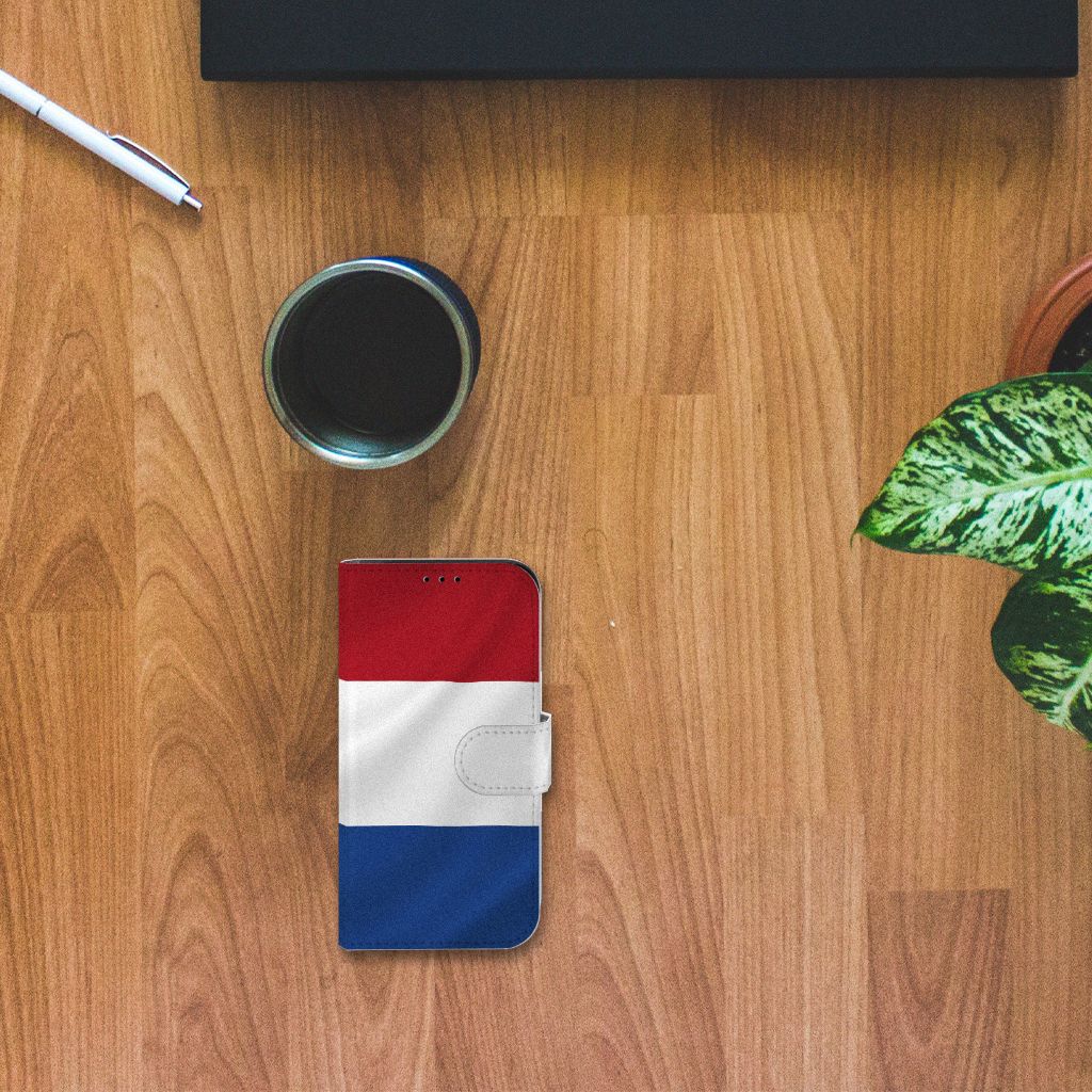 iPhone 13 Mini Bookstyle Case Nederlandse Vlag met artistiek ontwerp op houten tafel.