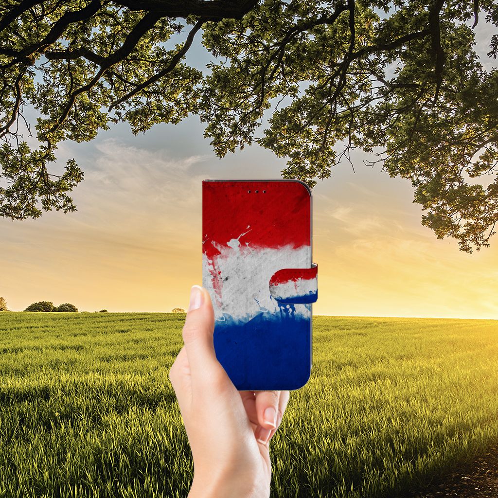 Apple iPhone 13 Bookstyle Case Nederland met Nederlandse vlag in een hand voor een landschap.