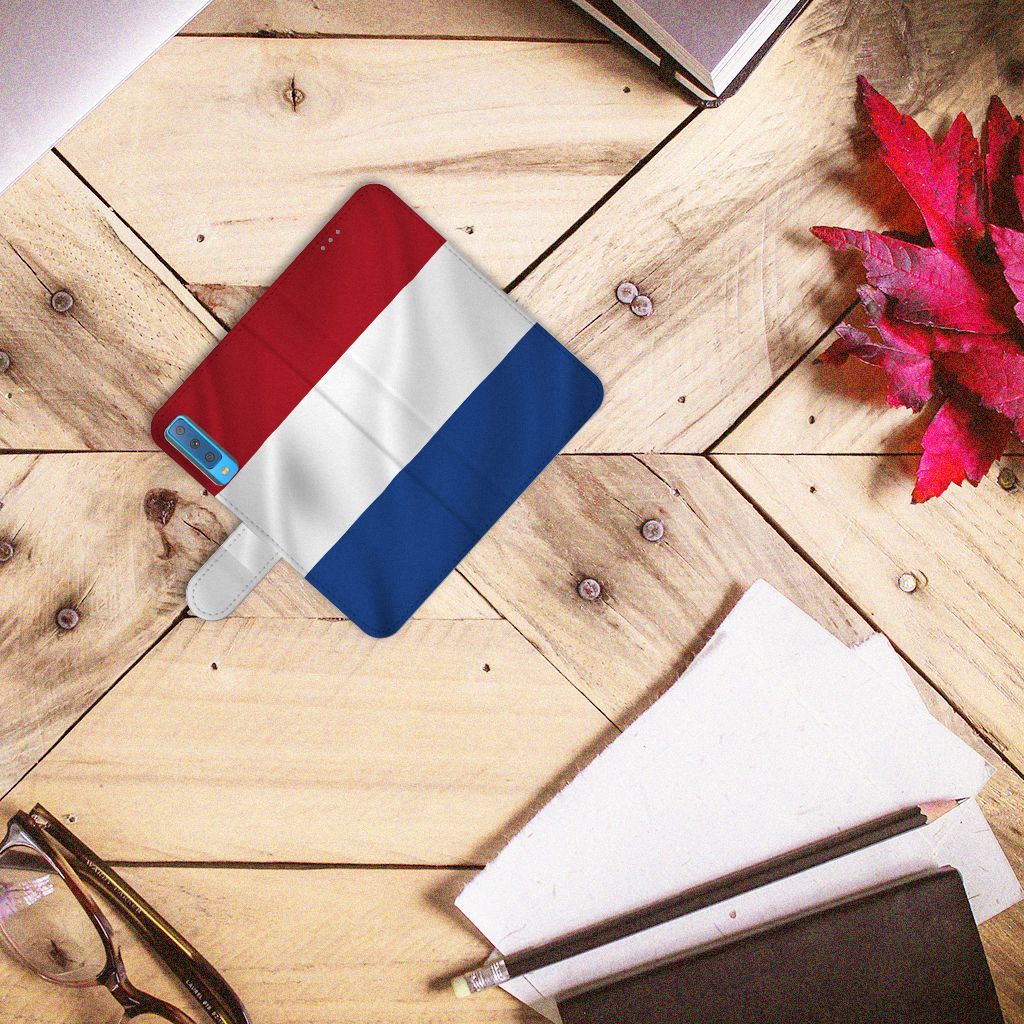 Samsung Galaxy A7 (2018) Bookstyle Case Nederlandse Vlag op een houten tafel met kantoorbenodigdheden.