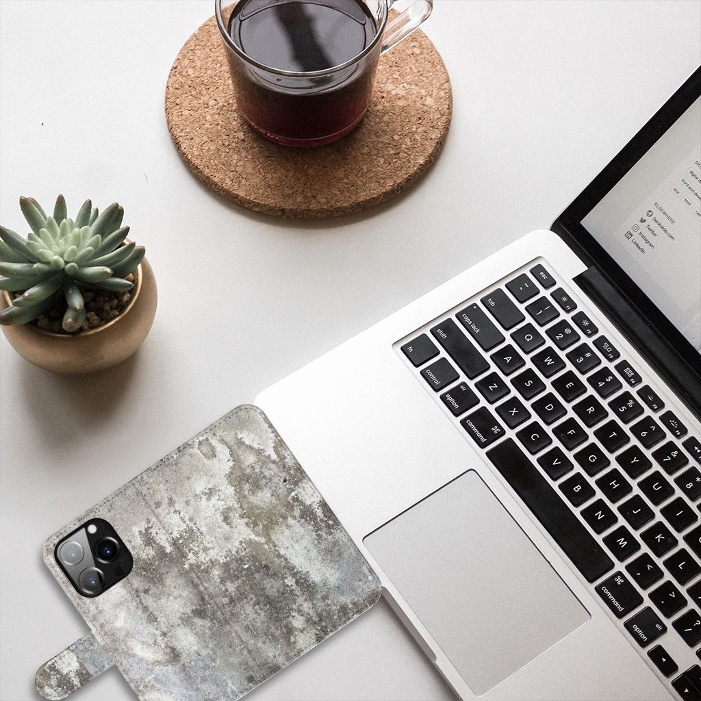 iPhone 14 Pro Bookcase Beton Print met een realistische betonlook naast een laptop en een plantaardige decoratie.