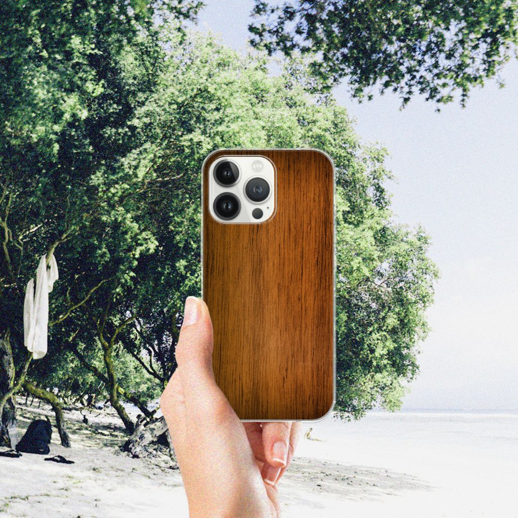 iPhone 13 Pro Max Bumper Hoesje Donker Hout in hand tegen een groene achtergrond met bomen.