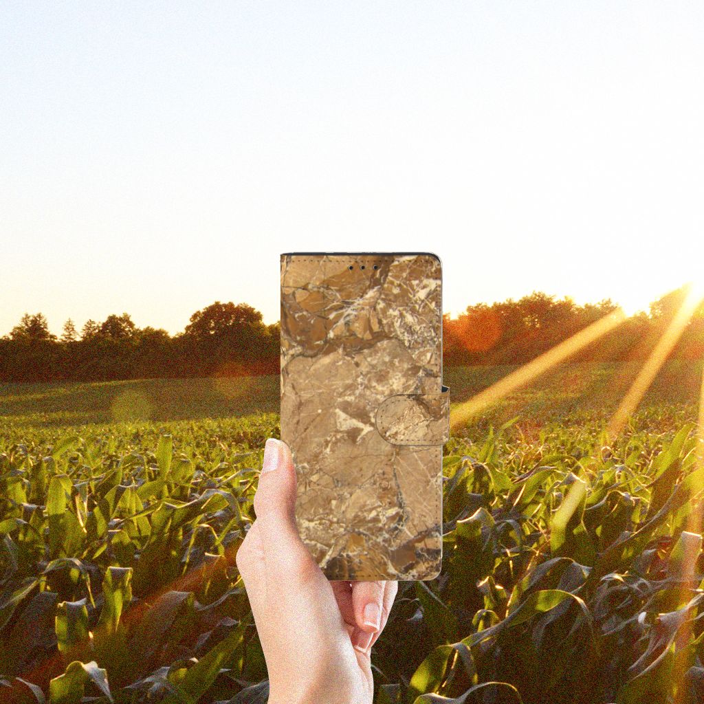 Motorola Edge 20 Lite Bookcase Marmer Creme in hand against a sunset backdrop over green fields.