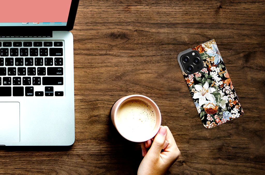 Smart Cover voor iPhone 13 Pro Dark Flowers ligt op een bureau naast een laptop en een kop koffie.