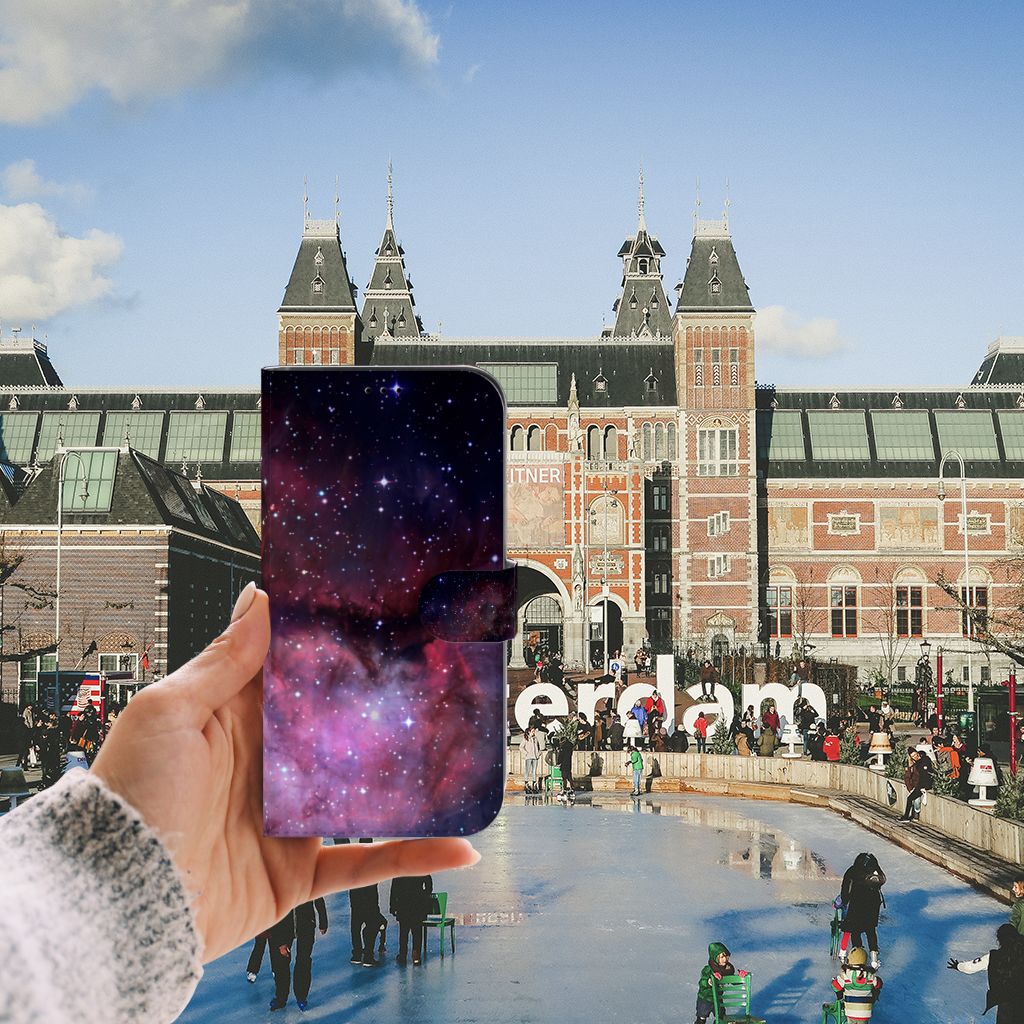 Hand holding a Book Case voor iPhone 13 Pro Max Galaxy with a galaxy design in front of the Amsterdam city scene.