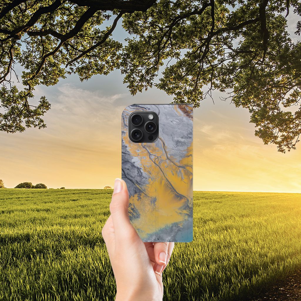 iPhone 15 Pro Max Standcase Marble Blue Gold in een hand tegen een zonnige achtergrond