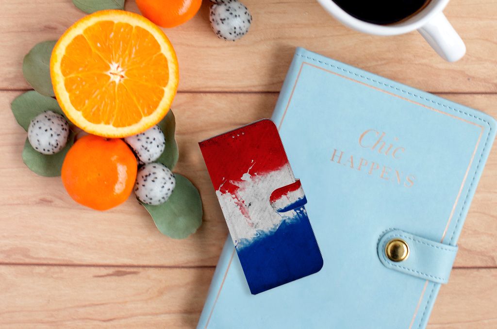 Motorola Moto G60 Bookstyle Case Nederland met artistieke Nederlandse vlag op een houten tafel met fruit en notebook.
