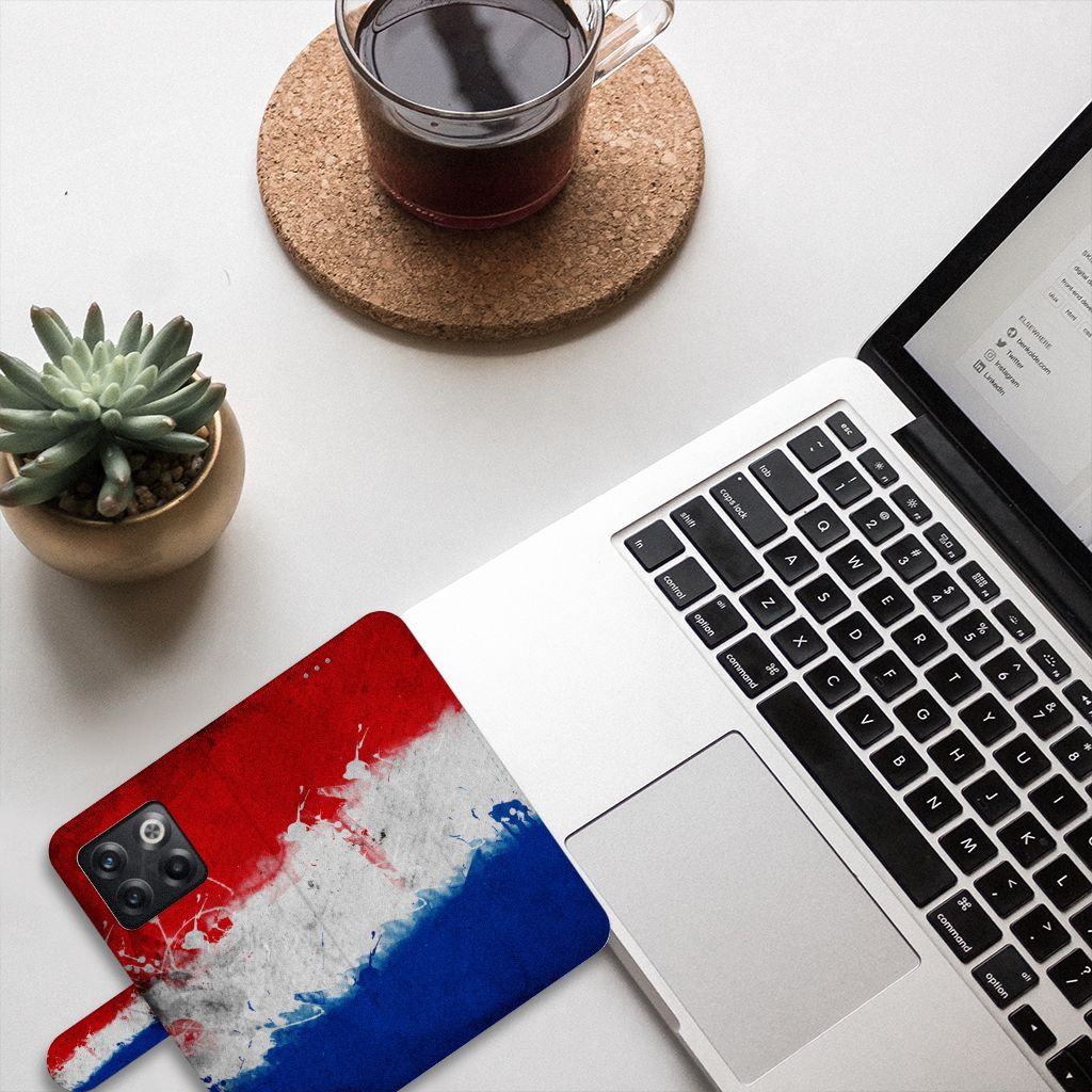 OnePlus 10T Bookstyle Case Nederland naast een laptop met een kop koffie en een plant, design met Nederlandse vlag.