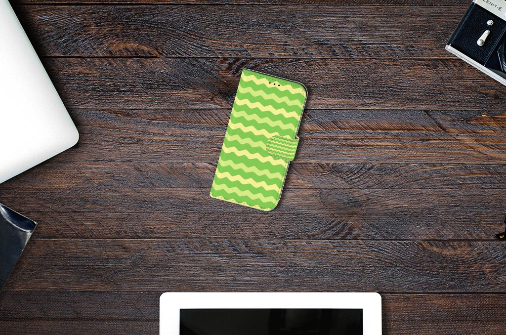 Apple iPhone 13 Telefoon Hoesje Waves Green met groen golvend design op een tafel.