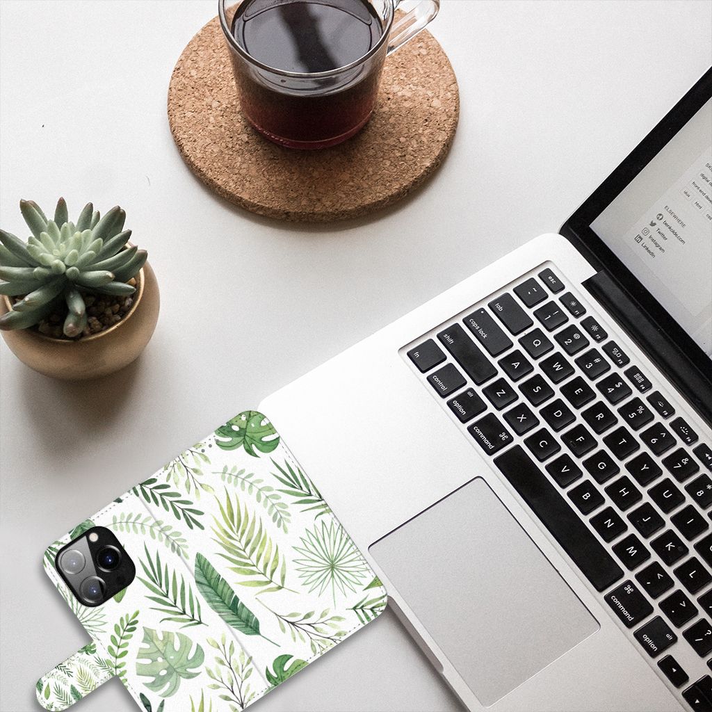 iPhone 14 Pro Hoesje Leaves met groen bladeren patroon op een bureau met een laptop en een kopje koffie.