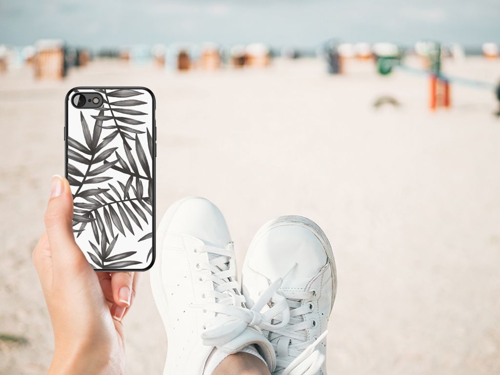 iPhone SE 2022 | SE 2020 | 7/8 Bloemen Hoesje Leaves Grey op een strand met sneakers aan.