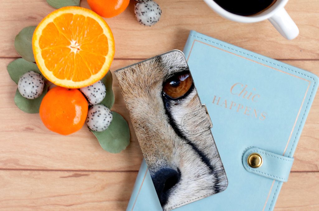 Xiaomi Redmi 10C Telefoonhoesje met Pasjes Cheetah, close-up van een cheeta oog op een houten ondergrond met fruit en notitieboek.