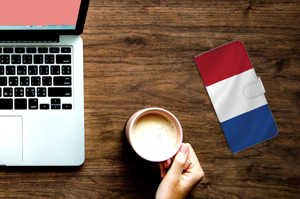 Sony Xperia 1 III Bookstyle Case Nederlandse Vlag naast een laptop en een kop koffie op een houten tafel.