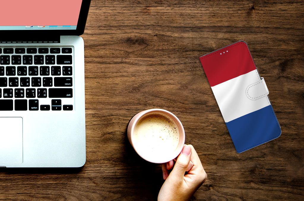 Xiaomi Redmi Note 11/11S Bookstyle Case Nederlandse Vlag op een houten tafel met laptop en koffie.