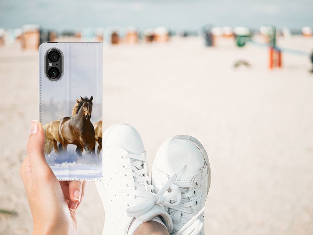 Sony Xperia 5 V Hoesje maken Paarden met paardenprint, handgehouden op het strand met sneakers.