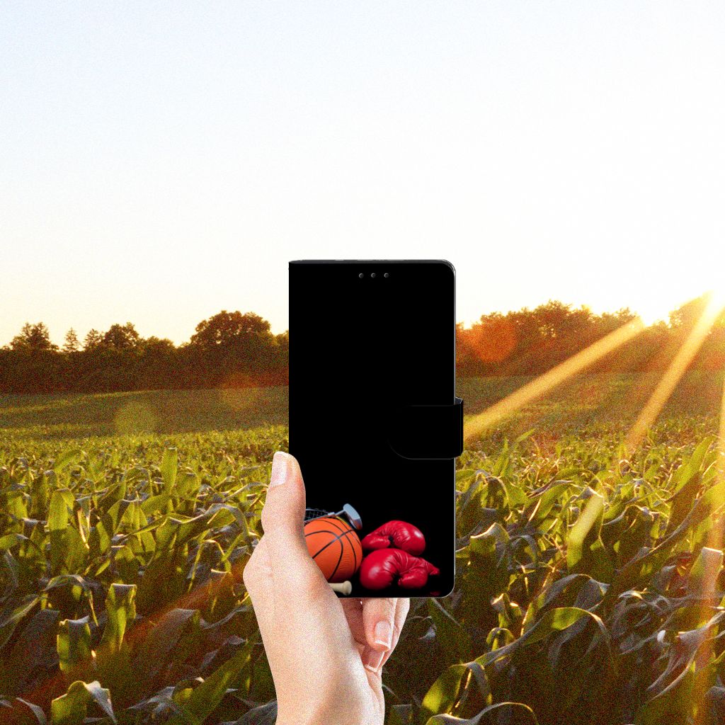 Hand holding Motorola Edge 20 Lite Wallet Case met Pasjes Sports with basketball and boxing gloves design in a sunny field.