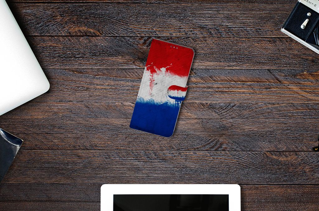 Motorola Moto G9 Plus Bookstyle Case Nederland met artistieke versie van de Nederlandse vlag op een houten tafel.