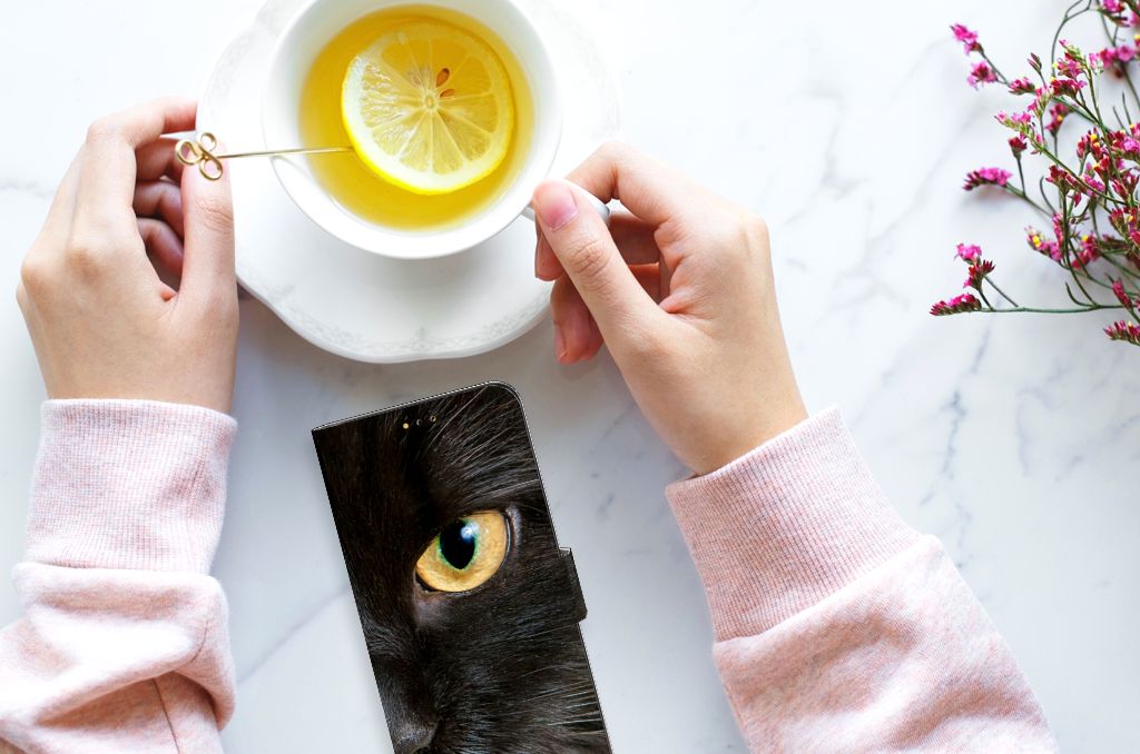 Samsung Galaxy A14 5G Telefoonhoesje met Pasjes Zwarte Kat op een tafel met thee en een schijfje citroen.