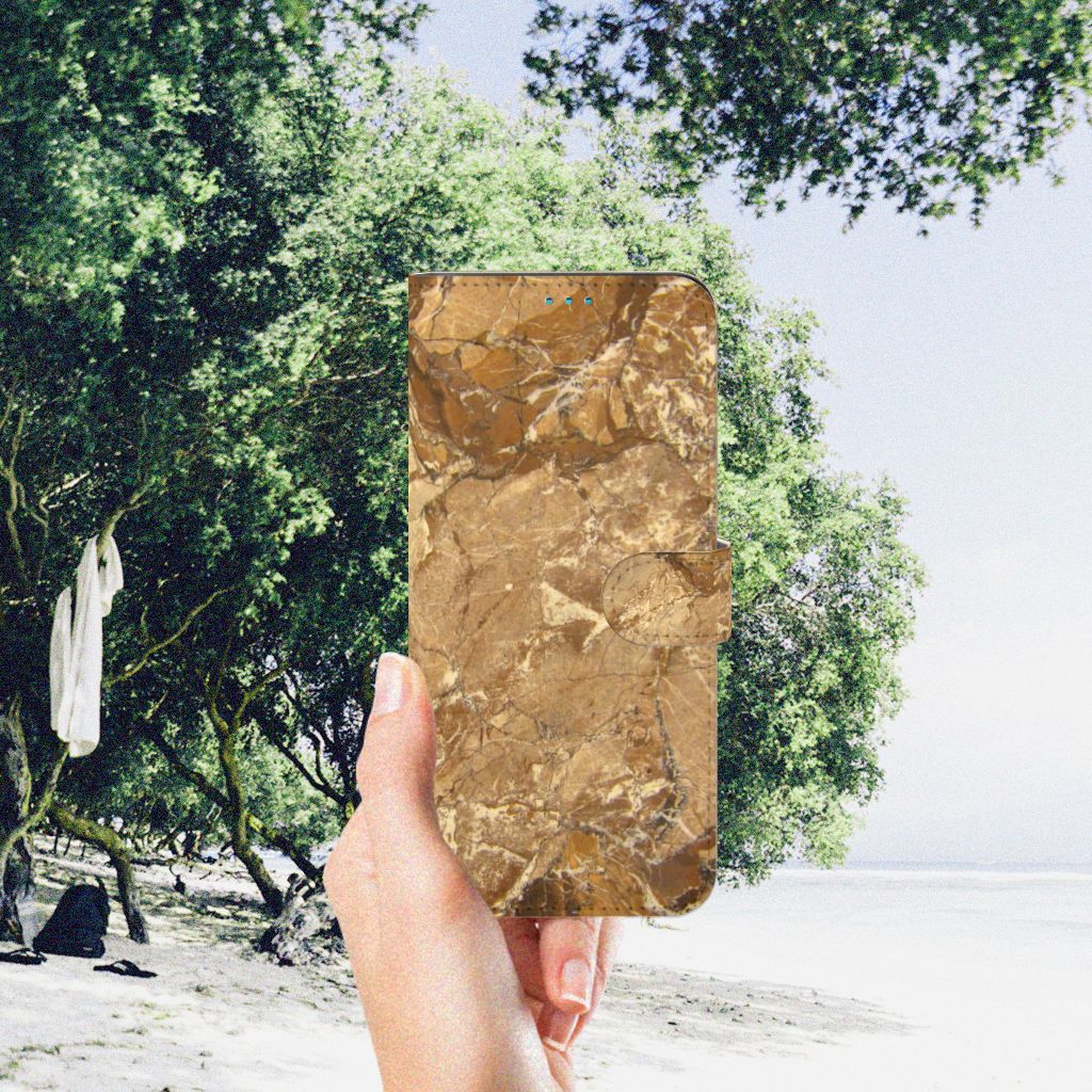 Motorola Moto G51 5G Bookcase Marmer Creme met luxe marmerdesign in hand, op een strandachtige achtergrond.