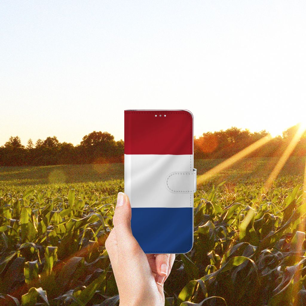 Samsung Galaxy A71 Bookstyle Case Nederlandse Vlag in een hand, met een zonsondergang op de achtergrond.