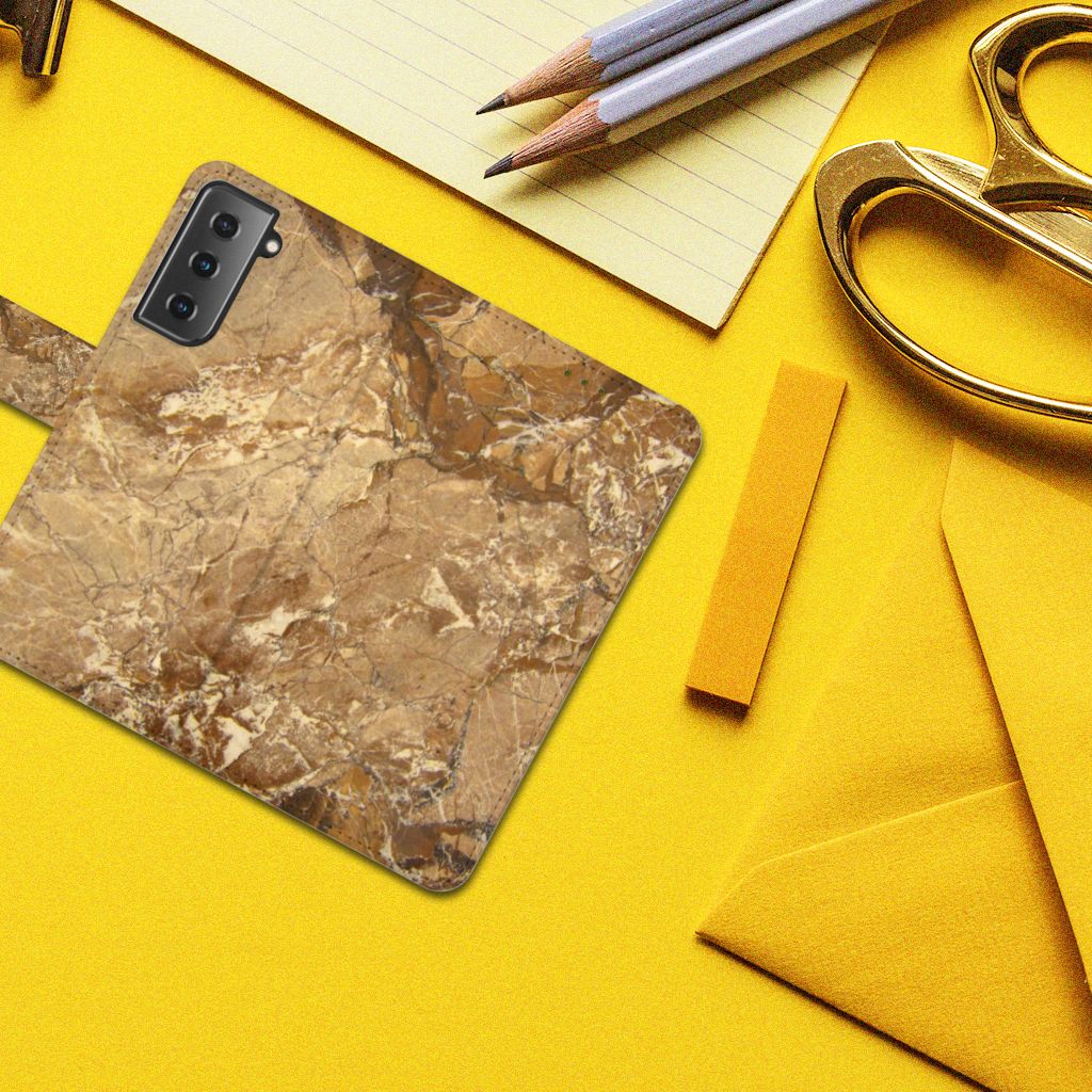 Samsung Galaxy S21 Bookcase Marmer Creme op een gele achtergrond met kantoormaterialen.