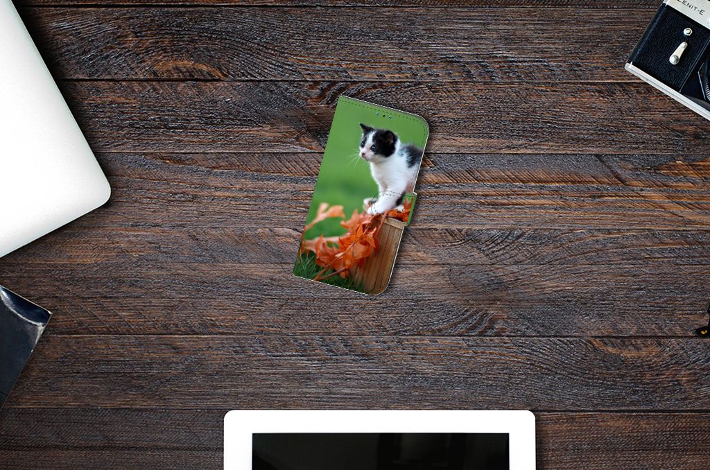 iPhone 14 Pro Telefoonhoesje met Pasjes Kitten bovenop een tafel met laptop en telefoon.